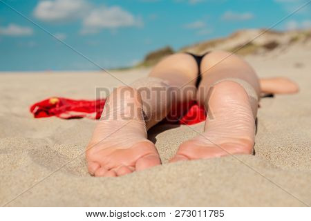 Single Topless Young Woman In Swimsuit At Sand Sea Beach With Blue Sky And Clouds Tanning Lying