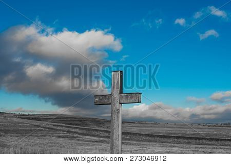 Simple Oak Catholic Cross In Black And White, Blue Sky With Stormclouds On The Background.