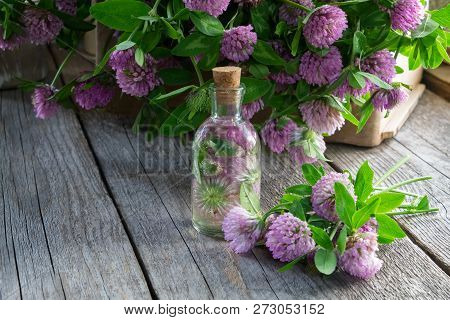 Bottle Of Clover Tincture Or Infusion And Clover Flowers Bunch In Wooden Crate.