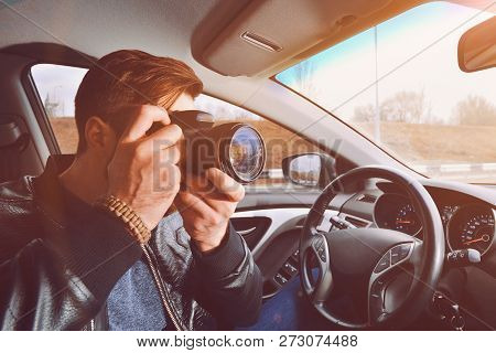 A Man Is Taking Pictures From A Car Window. Photographer Traveler. The Work Of A Private Detective