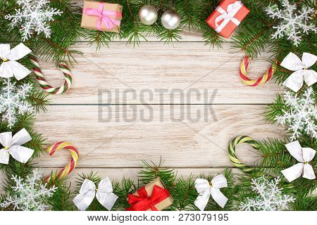 Christmas Frame Made Of Fir Branches Decorated With Snowflakes, Baws, Candy Canes And Boxes On A Lig