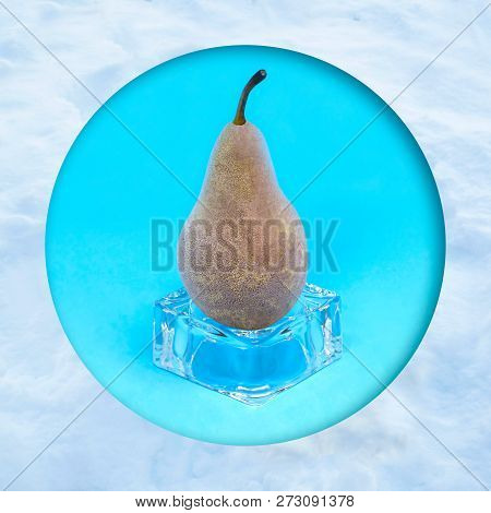Frozen Pear On Ice Cube In Snow Frame. Creative Concept: Quickly Frozen Fruits And Vegetables Retain