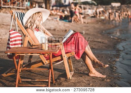 Girl Reading A Book While Sitting On Deck Chair