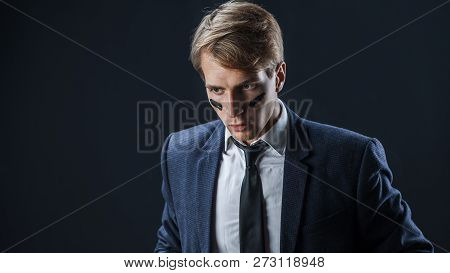 Serious And Thoughtful Young Man In A Business Suit With War Paint On His Face. Aggressive Business,