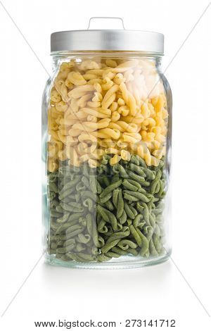 Uncooked spinach gemelli pasta in jar isolated on white background.