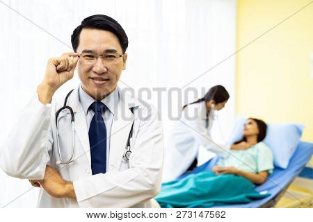 Portrait of Young adult Doctor with nurse and Patient in background.