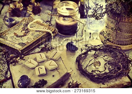 Still Life With Old Tarot Cards, Runes, Roots And Black Candle On Table. Magic Gothic Ritual. Wicca,