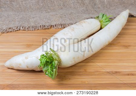 Two Fresh Washed Daikon Radishes With Torn Off Haulm On A Wooden Bamboo Cutting Board At Selective F