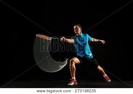 Young Man Playing Badminton Over Black Studio Background. Fit Male Athlete Isolated On Dark With Led