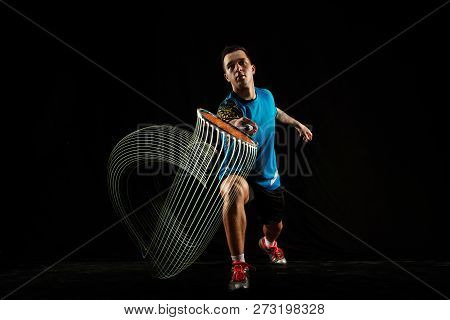 Young Man Playing Badminton Over Black Studio Background. Fit Male Athlete Isolated On Dark With Led