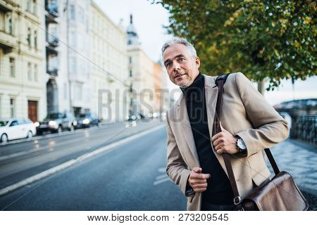 Mature Businessman Standing On The Street In City, Waiting For A Taxi Cab.
