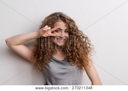 Young Beautiful Cheerful Woman In Studio, Fingers Forming V.