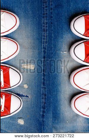 White And Red Sneakers On A The Ripped Denim Background.