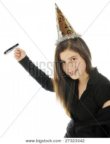 Una tween ragazza vestita di nero che celebra il nuovo anno con un noise maker e cappello partito d'argento.  Su 