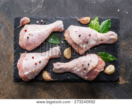 Chicken legs with spices and salt  ready for cooking on cutting board.