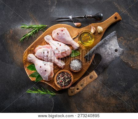 Chicken legs with spices and salt  ready for cooking on cutting board.