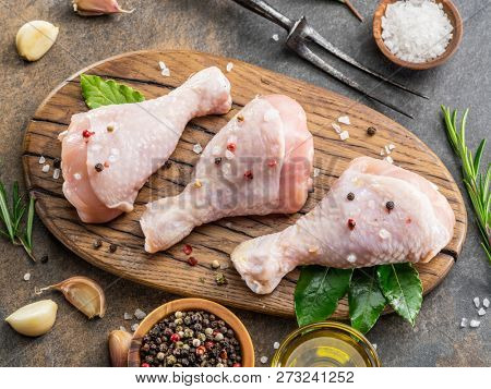 Chicken legs with spices and salt  ready for cooking on cutting board.