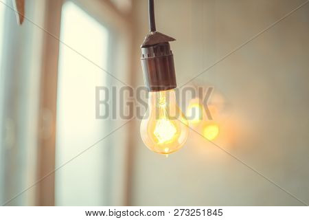 Retro Vintage Light Bulb With Led Technology Bult-in On Warm Light Yellow Tint And Black Background 
