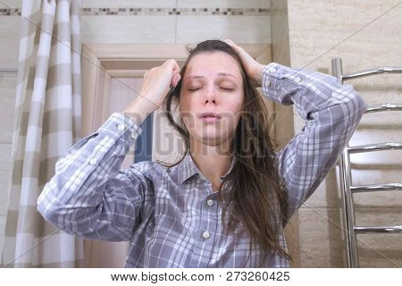 Sleepy Woken Woman Combs Her Hair Standing In Front Of A Mirror In The Bathroom.