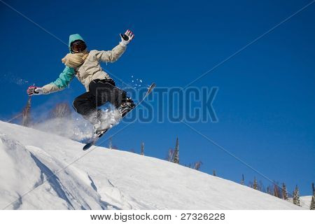 Snowboardista skoky vzduchem s tmavě modrou oblohou v pozadí
