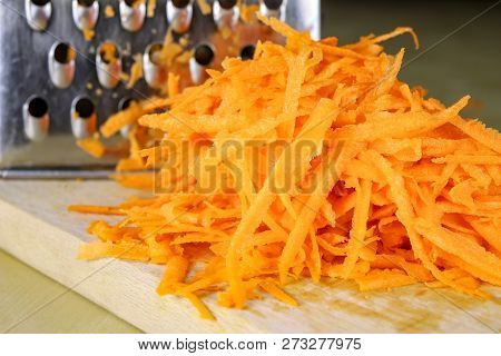Fresh Carrot Grated On A Metal Kitchen Grate. Vegetables Prepared For Salad With A Meal On The Kitch