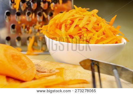 Fresh Carrot Grated On A Metal Kitchen Grate. Vegetables Prepared For Salad With A Meal On The Kitch