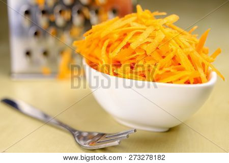 Fresh Carrot Grated On A Metal Kitchen Grate. Vegetables Prepared For Salad With A Meal On The Kitch
