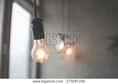Retro Vintage Light Bulb With Led Technology Bult-in On Warm Light Yellow Tint And Black Background 