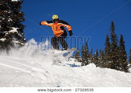 Snowboardista skoky vzduchem s tmavě modrou oblohou v pozadí