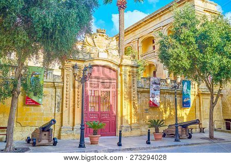 Mdina, Malta - June 14, 2018: The Beautiful Carved Entrance Gates To Palazzo Vihena And Two Cannons 