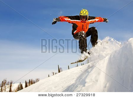 Snowboardista skoky vzduchem s tmavě modrou oblohou v pozadí