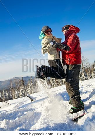 Snowboardisté skoky, tmavě modrou oblohou v pozadí