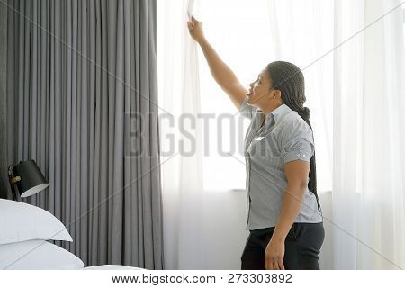 Maid Fixes A Curtain In The Room. Maid Making Bed In Hotel Room. Staff Maid Making Bed. African Hous