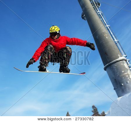 Snowboardista skoky vzduchem s tmavě modrou oblohou v pozadí