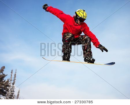 Snowboardista skoky vzduchem s tmavě modrou oblohou v pozadí