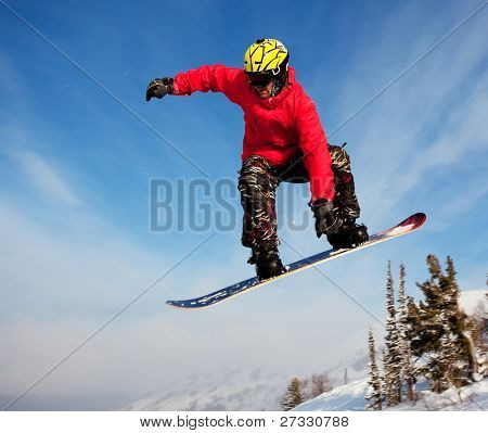 Snowboardista skoky vzduchem s tmavě modrou oblohou v pozadí