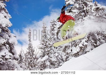 Snowboardista skoky vzduchem s tmavě modrou oblohou v pozadí