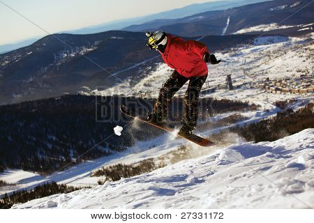 Snowboardista skoky vzduchem s modrou oblohou v pozadí
