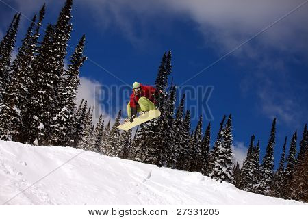 Snowboardista skoky vzduchem s tmavě modrou oblohou v pozadí