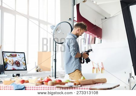 Portrait Of Smiling Male Photographer Looking At Pictures In Camera While Working In Photo Studio Sh