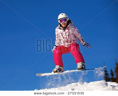 Snowboardista skoky vzduchem s tmavě modrou oblohou v pozadí