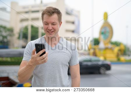 Young Happy Tourist Man Using Phone Against Ratchadamnoen Street In Bangkok