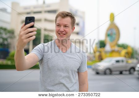 Young Happy Tourist Man Taking Selfie Against Ratchadamnoen Street In Bangkok