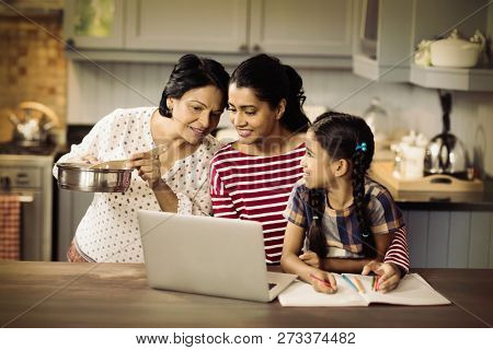Multi-generation family using laptop in kitchen at home