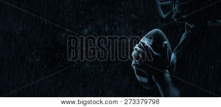 American football player standing with rugby helmet and ball against old weathered wall