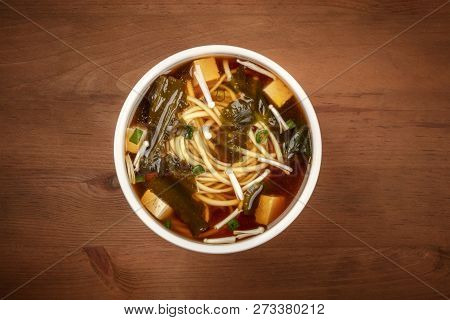 An Overhead Photo Of A Bowl Of Miso Soup With Tofu, Scallions, Noodles, Wakame Seaweed And Enoki Mus