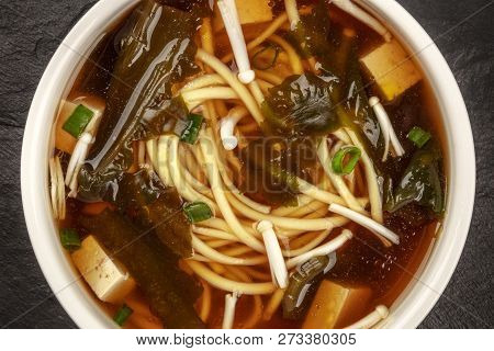A Closeup Of A Bowl Of Miso Soup With Tofu, Scallions, Noodles, Wakame, And Enoki Mushrooms, Shot Fr