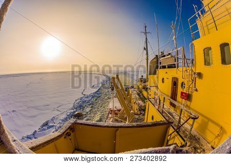  Dim polar sun in Lapland. The strip of ice crumb spreads behind the icebreaker. The excursion to the arctic tourist cruise on the sea icebound. The concept of active and extreme tourism