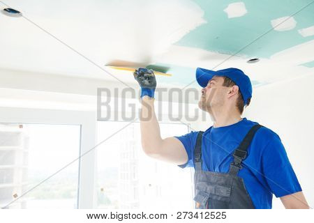 refurbishment. Plasterer spackling a gypsum plasterboard ceiling with putty