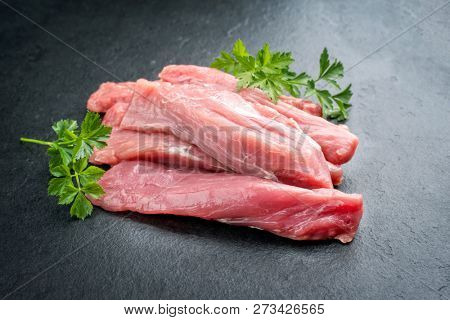 Raw suckling pig fillet offered on a black slate slab as closeup